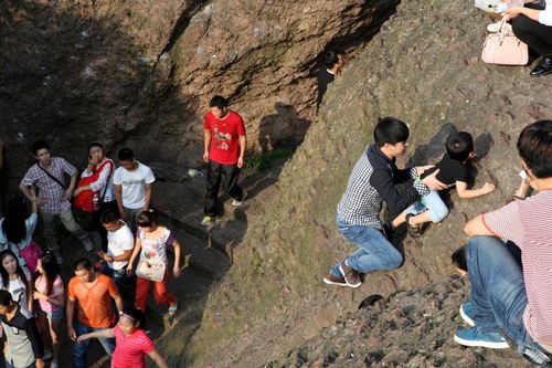 杭州宝石山人潮拥挤 游客带小孩爬山崖抄近道 