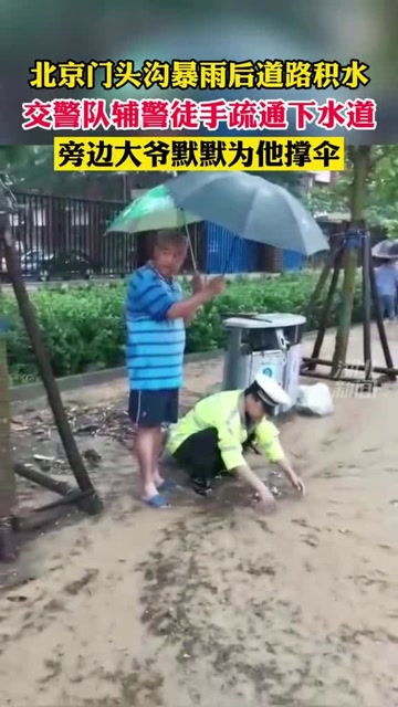 7月18日,北京 暴雨过后路面积满污水,一位辅警脚踩泥水中,手伸进下水道掏出脏物 致敬 