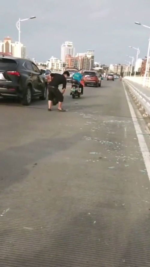 车祸过后的路面碎玻璃满地,小伙为过往行人清理路面 