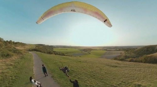 英国一男子乘滑翔伞低空飞行 与地上的人一起踢足球